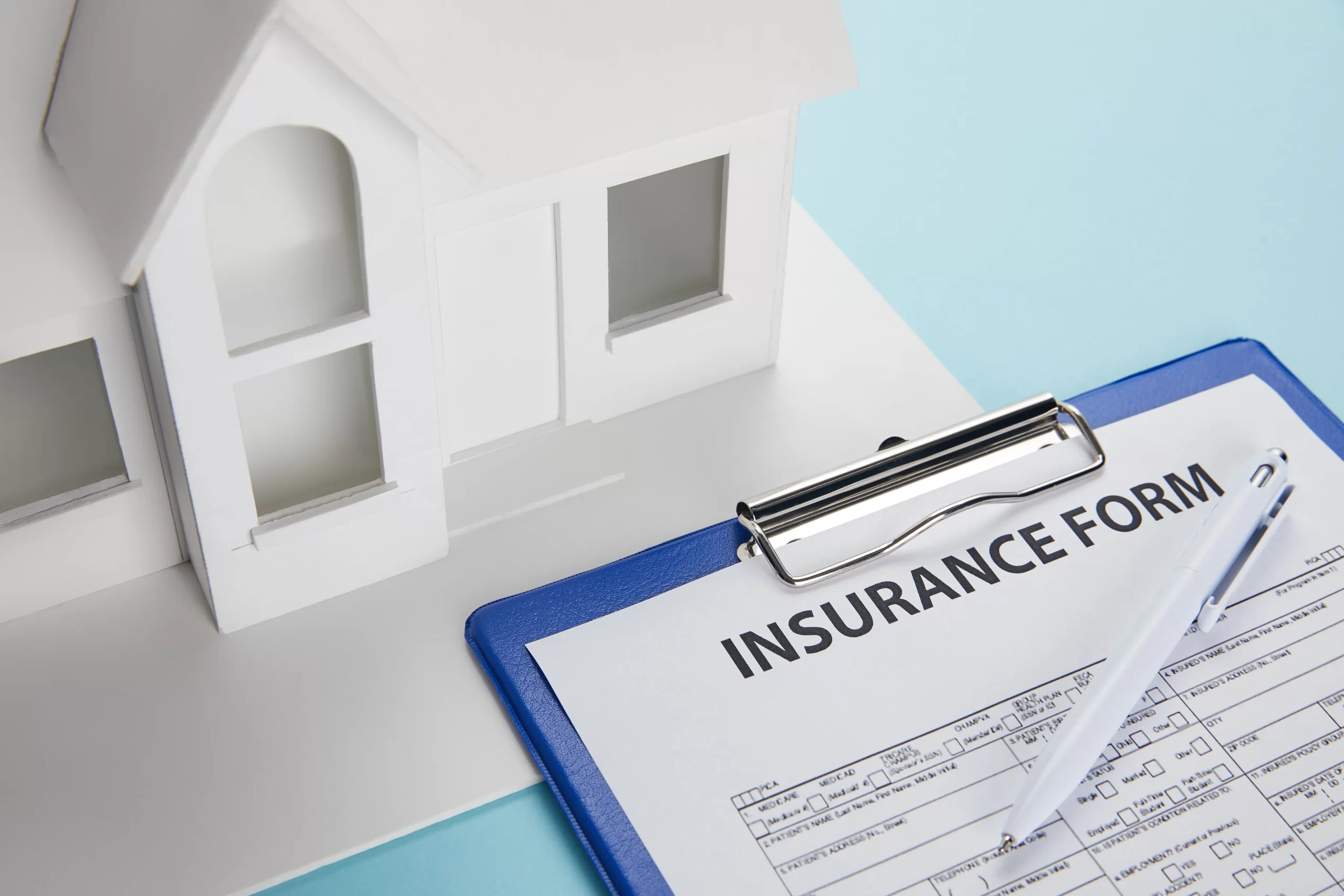 Close up view of insurance form an a small house in front of it