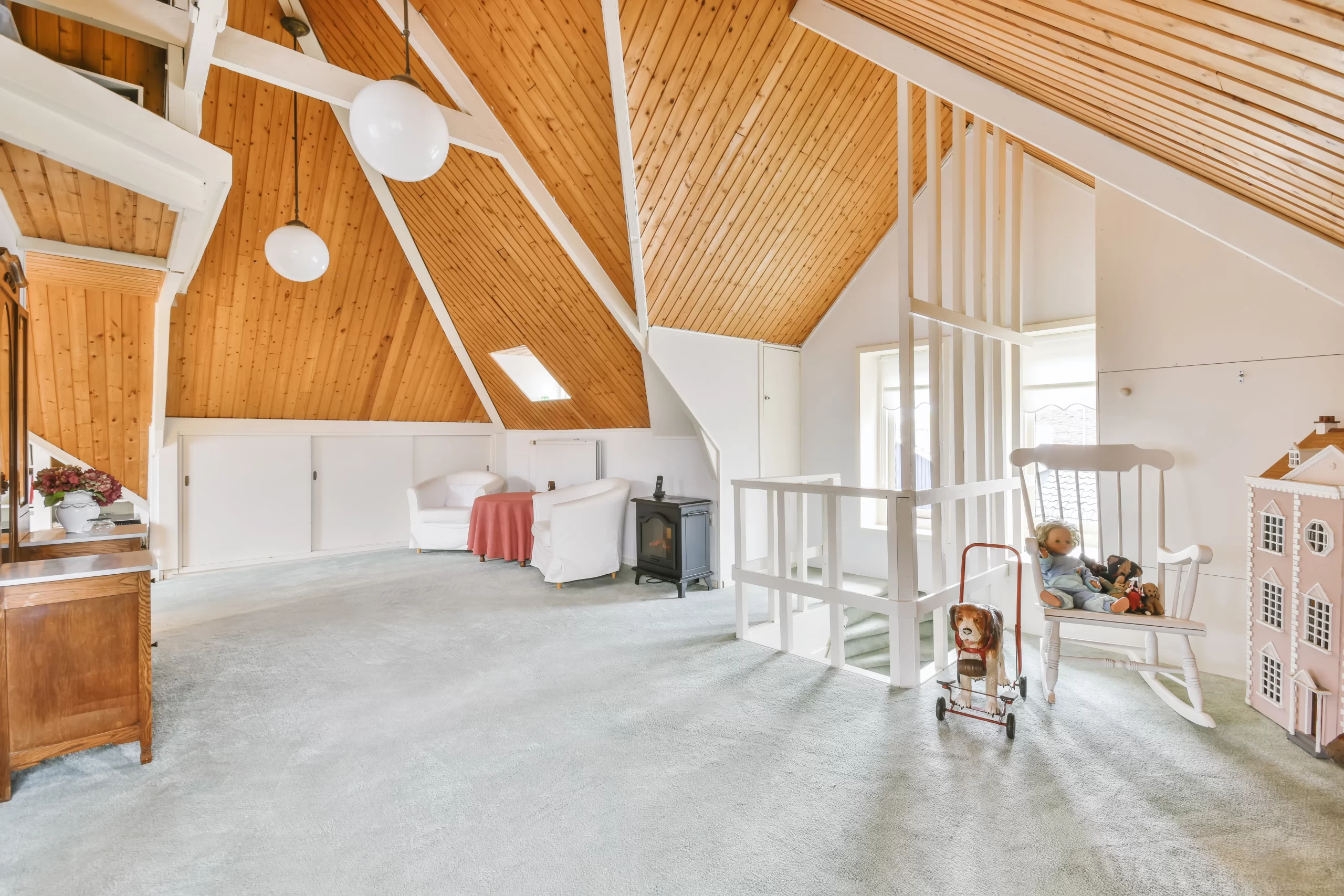 Cozy furnished attic with a high wooden ceiling.