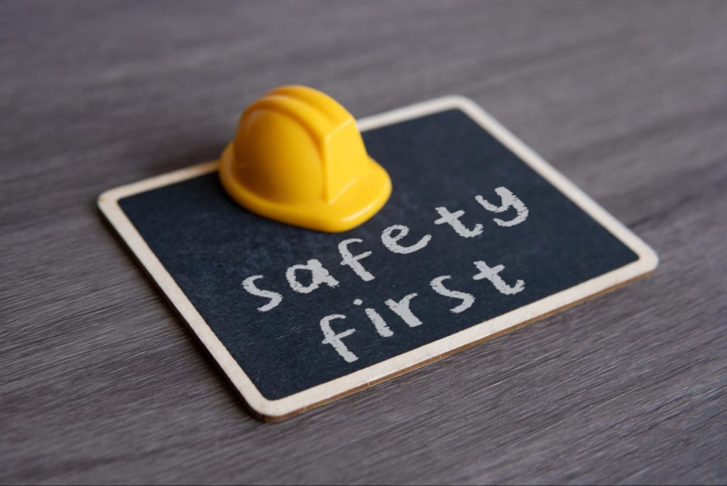 Hard hat on a chalkboard that has the words “safety first” on it.