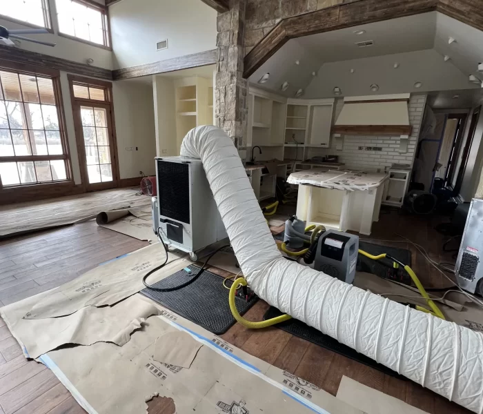 A partially renovated interior featuring exposed beams, a large duct system, and construction materials scattered across the wooden floor.