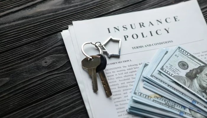 Home insurance policy with keys and dollar money on top of it.
