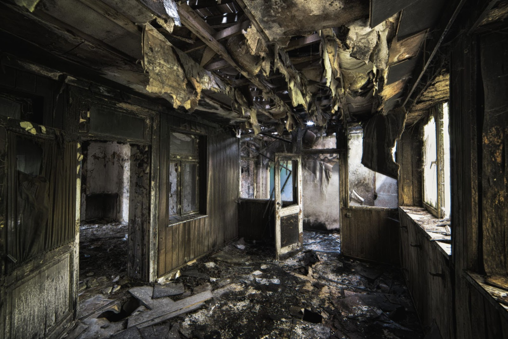 A room interior with catastrophic fire damage to the ceilings, walls, and flooring.