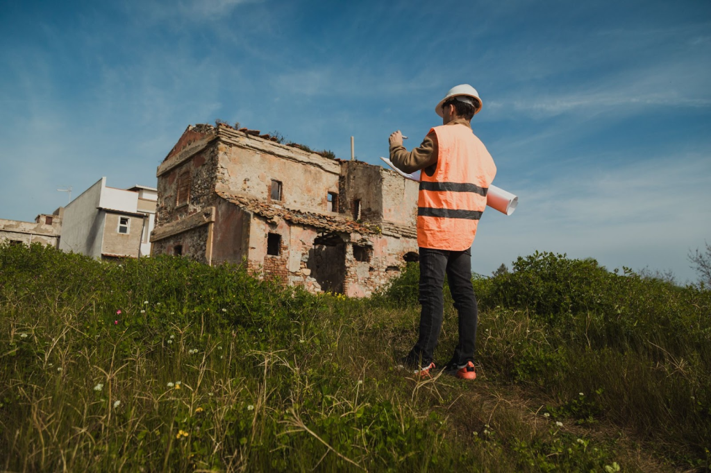 An inspector takes notes on a restoration project outdoors.